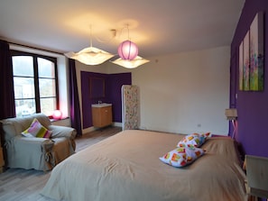 A bedroom with a bed, a window, a vanity, and a chair.