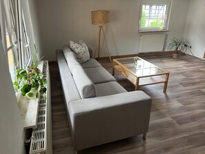 A modern living room with a grey sofa, a glass coffee table, and a floor lamp.