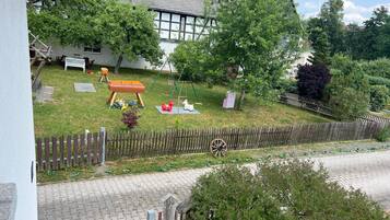 A residential property with a grassy yard, a wooden fence, and a swing set.