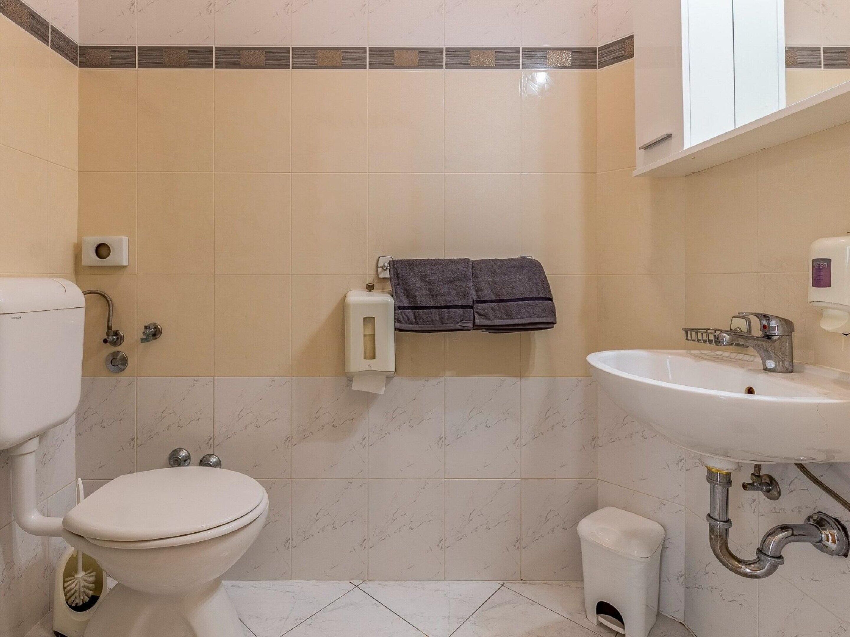 Un baño con inodoro, lavamanos y perchero para toallas.