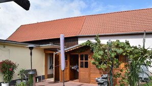 A house with a red-tiled roof, a wooden door, and a garden with plants and a stone feature. - Pleasant Apartment in Veckenstedt near Ilsenburg (Nordharz)