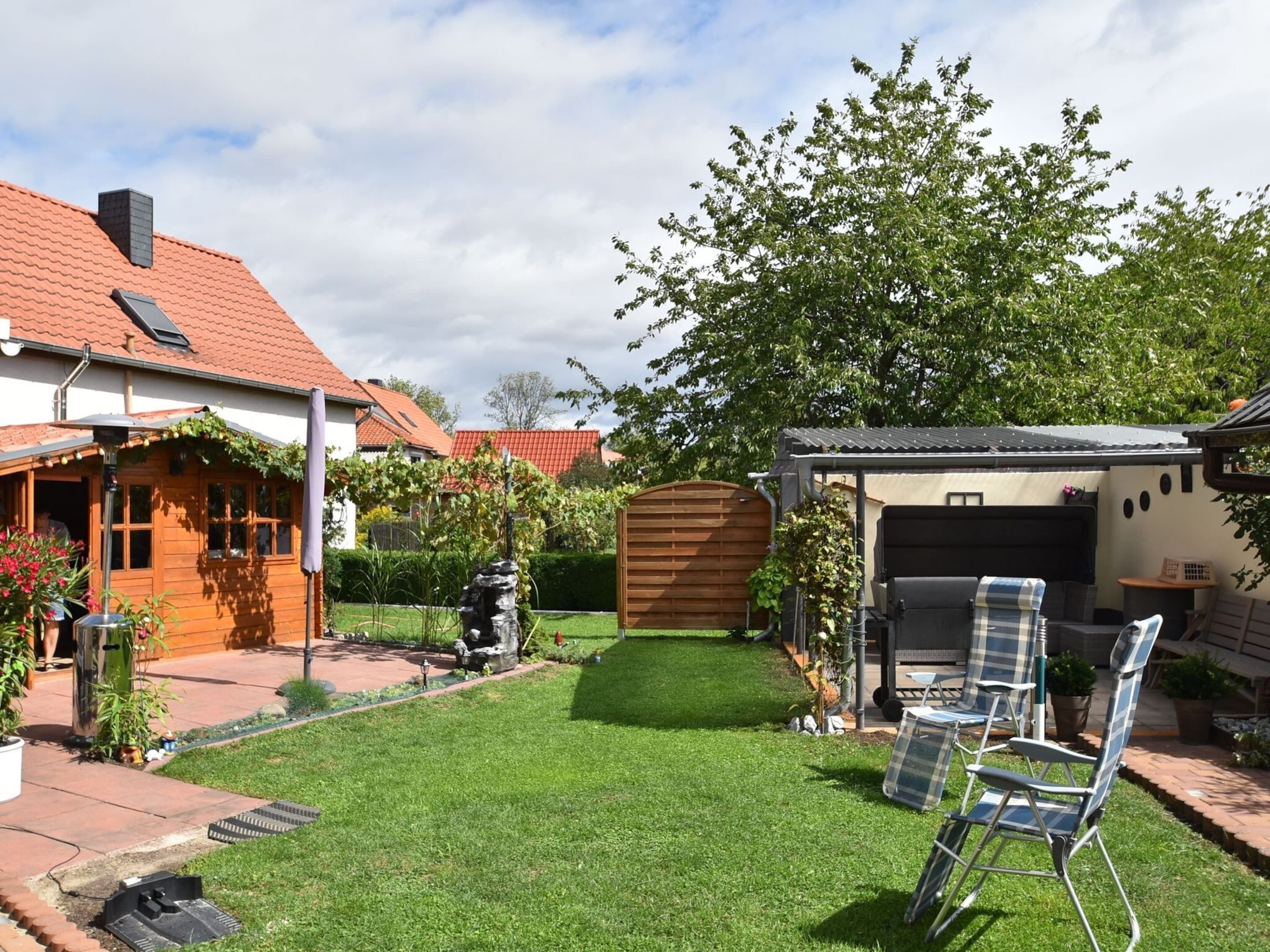 Ein gepflegter Garten mit Rasenfläche, Grillplatz und Holzzaun.