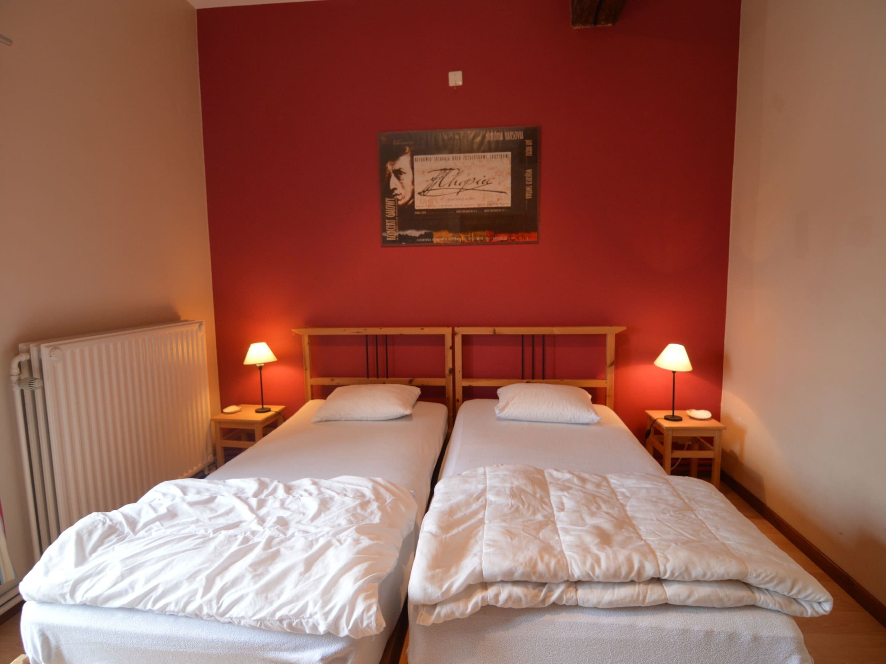 Ein Zimmer mit zwei Einzelbetten, einem Heizkörper und einem Poster an der Wand.