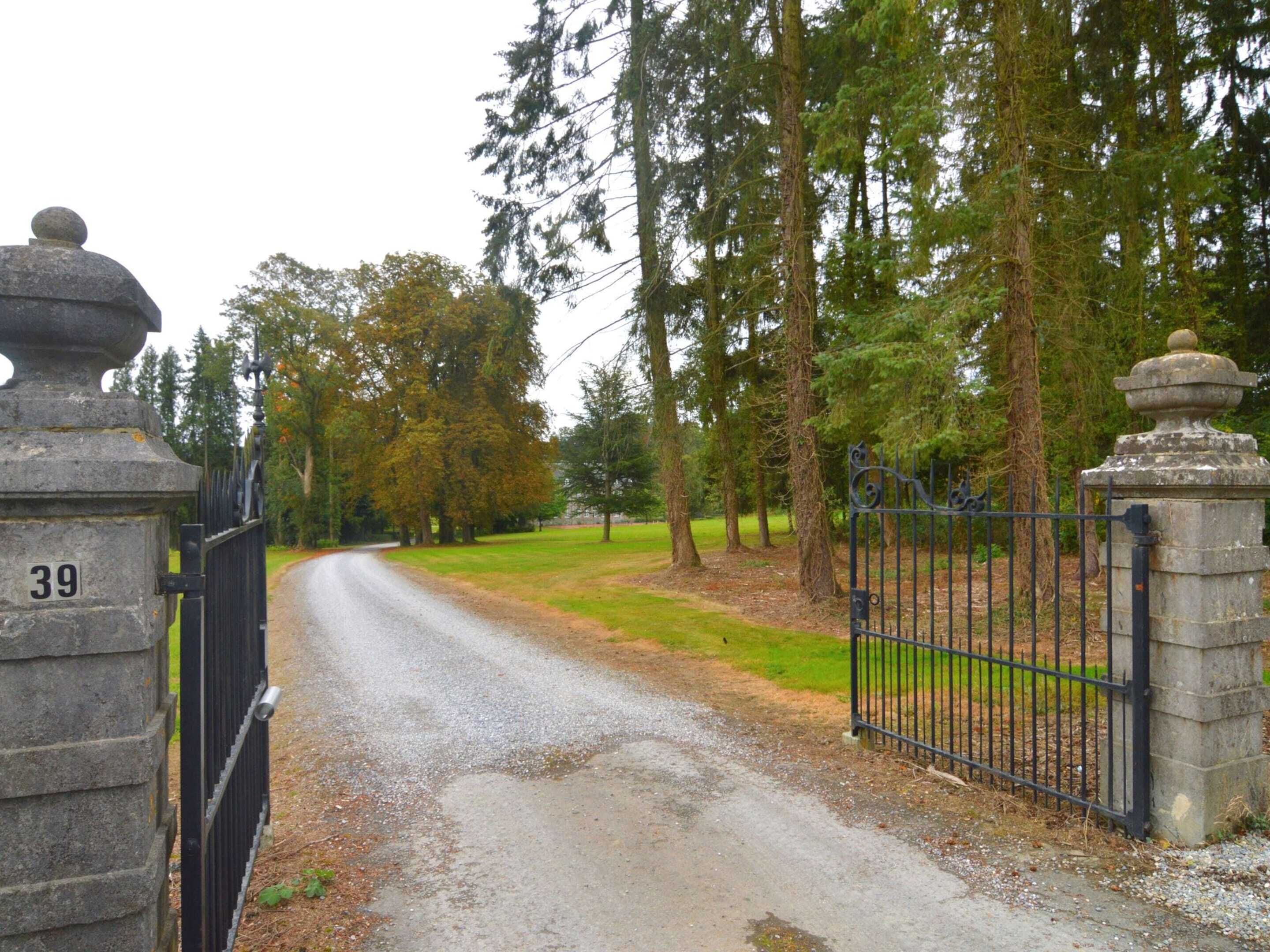 A gravel driveway leading to a gated entrance with a stone pillar marked '39'.