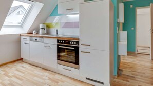 A modern kitchen with white cabinetry, a built-in oven, and a window above the sink. - Pleasant Holiday Home in Zierow near Sea (Zierow)