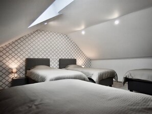 Ein modernes Schlafzimmer mit schrägen Wänden, zwei Betten und einer Wand mit Muster.