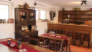 A traditional kitchen with wooden cabinets, a bar area, and a dining table set with chairs. - Cozy Apartment With Pool & Forest (Kirchdorf)