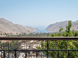 A balcony with wrought iron railings overlooking a coastal landscape with mountains and a body of water. - Pretty Holiday Home in Symi Island With Balcony (Symi)