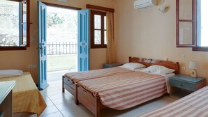 A bedroom with two beds, a wooden headboard, a nightstand with a lamp, and an air conditioning unit. - Pretty Holiday Home in Symi Island With Balcony (Symi)