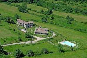 An aerial view of a rural property with a large stone house, a swimming pool, and surrounding greenery. - Farmhouse Near Lake Trasimeno With Pool (Passignano sul Trasimeno)