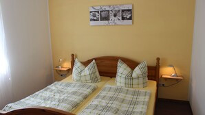 A double bed with a plaid bedspread, two bedside tables with lamps, a wall-mounted picture, and a wooden headboard. - Chicke Ferienwohnung in Struppen (Struppen)