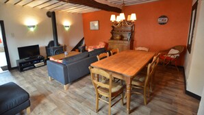 A living room with a wooden dining table, sofa, and television. - Holiday House in Horse Riding School near Stavelot & Spa Circuit (Stavelot)