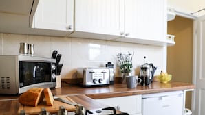 A kitchen with a microwave, toaster, coffee maker, and a gas stove.