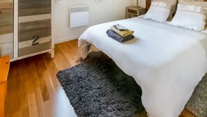 A neatly made bed with pillows and folded towels, a bedside table with a lamp, and a window with curtains. - Enticing Holiday Home in Treignes near Forest (Viroinval)