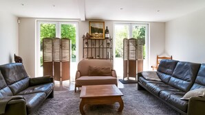 A living room with two leather sofas, a wooden coffee table, and a large window with shutters. - Enticing Holiday Home in Treignes near Forest (Viroinval)