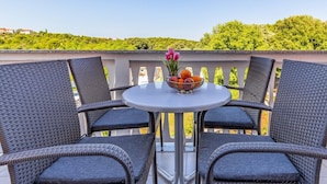 A balcony with wicker chairs and a table, a bowl of fruit, and a vase of flowers. - Graceful Apartment in Banjole near Beach Centinera (Medulin)