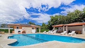 A swimming pool with a sun terrace, lounge chairs, and a covered area with a table and chairs. - Graceful Apartment in Banjole near Beach Centinera (Medulin)