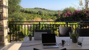 An outdoor patio with a laptop on a table, surrounded by chairs and potted plants, overlooking a lush landscape. - Beautiful, Modern, Luxuriously Villa, Private Swimming Pool 8 p NW Coast, Crete (Rethymno)