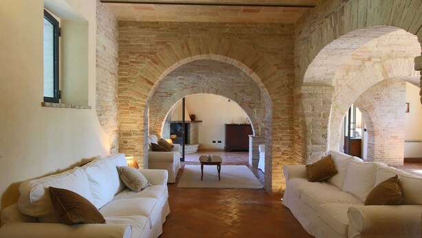 A cozy living room with two white sofas, a coffee table, and a fireplace. - Villa with Private Pool on an Estate near Assisi (Assisi)