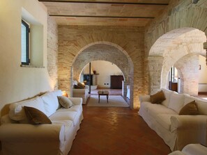 A cozy living room with two white sofas, a coffee table, and a fireplace. - Villa with Private Pool on an Estate near Assisi (Assisi)