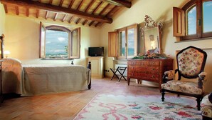 A bedroom with a bed, a dresser, a chair, a television, and a window with a view. - Villa with Private Pool on an Estate near Assisi (Assisi)
