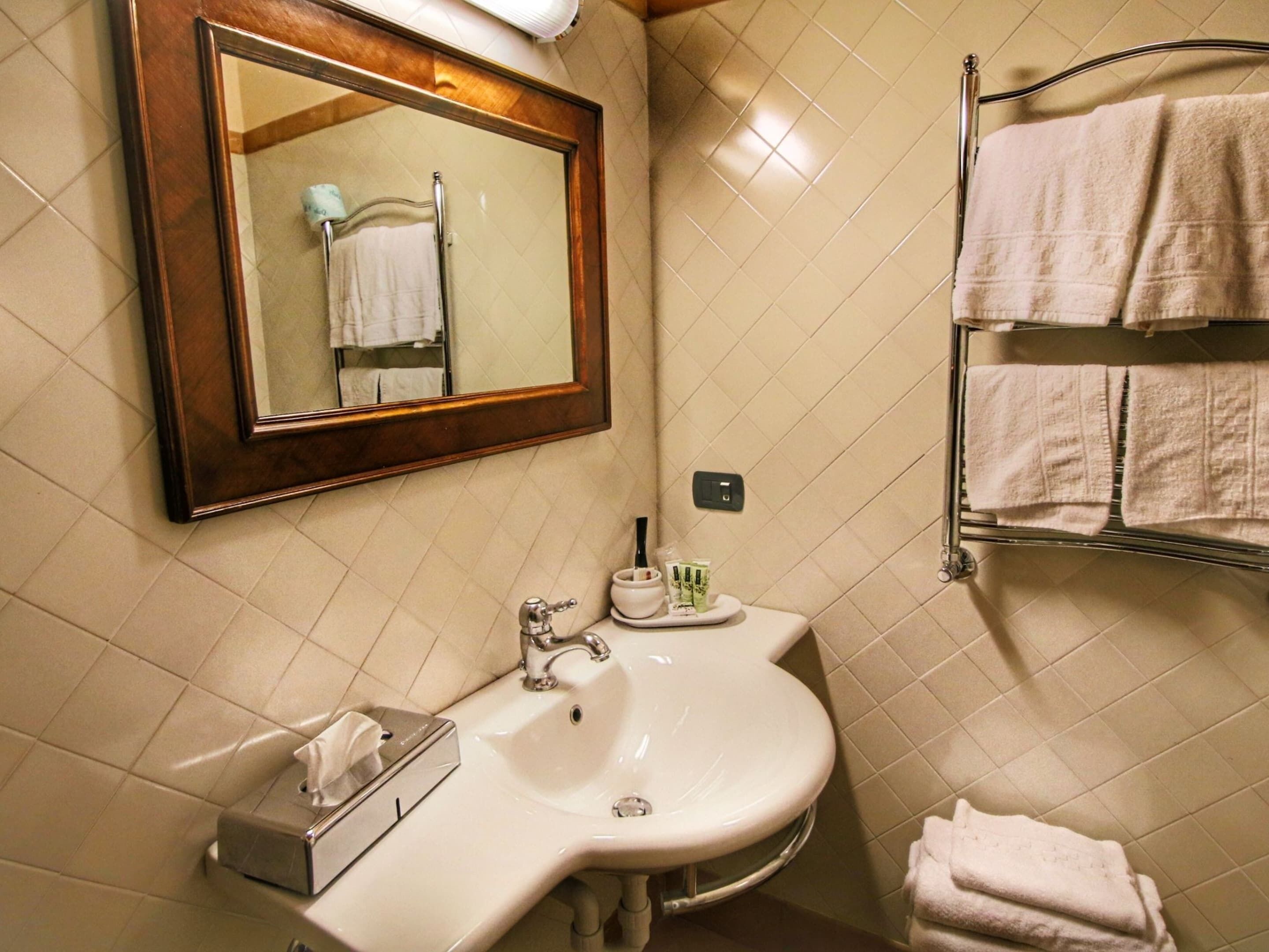 A bathroom with a sink, mirror, and towel rack.