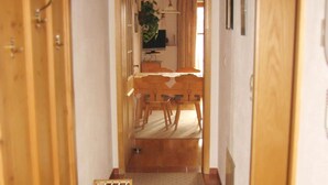 A hallway leading to a dining area with a wooden table and chairs, a plant, and a television. - Apartment in Ingenried With Bavarian Alps View (Ingenried)