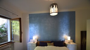 A bedroom with a bed, two bedside tables with lamps, a window, and a radiator. - Rustic Villa With Lake Views (Trarego Viggiona)