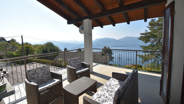 A balcony with wicker furniture, a view of the sea, and mountains in the background. - Rustic Villa With Lake Views (Trarego Viggiona)