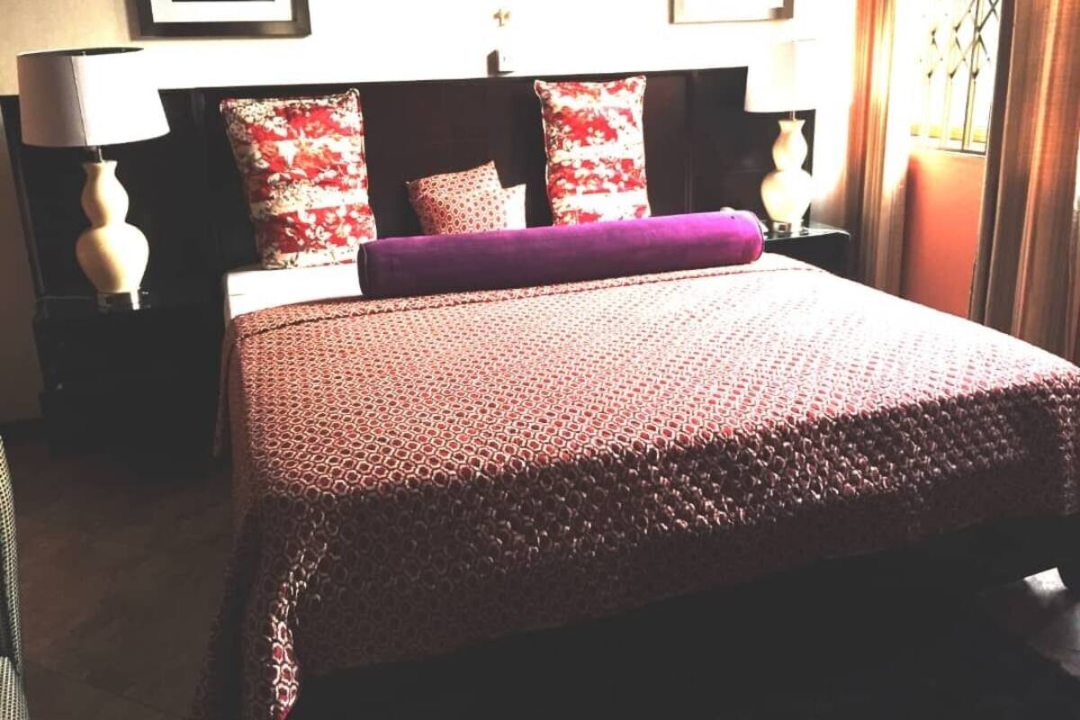 A neatly made bed with a patterned bedspread, two pillows, and a matching throw.