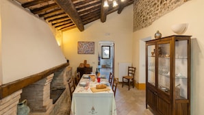 Un comedor con una mesa dispuesta para cuatro, un mueble de madera con puertas de cristal y una pared de piedra.