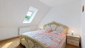 Een slaapkamer met een bed, nachtkastje en een raam.