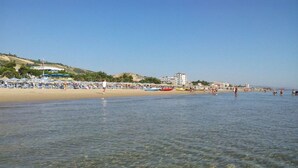 A beach with clear shallow waters, umbrellas, and beachgoers. - Mansion in Case Alte With Pool & Nature Trails (Sant'Omero)