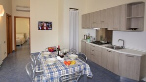 A dining area with a table set for four, a kitchen with modern appliances, and a living area visible through an open door. - Mansion in Case Alte With Pool & Nature Trails (Sant'Omero)