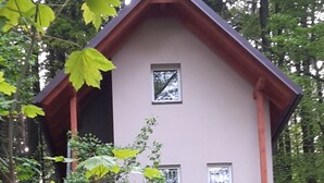 Et tosset etagehus med balkon, omgivet af træer.