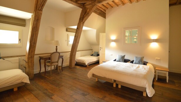 Een slaapkamer met een houten plafond, twee bedden, een bureau en een stoel.