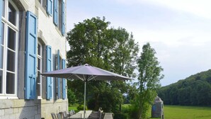 Een terras met buitenmeubels, een tafel en een paarse parasol.