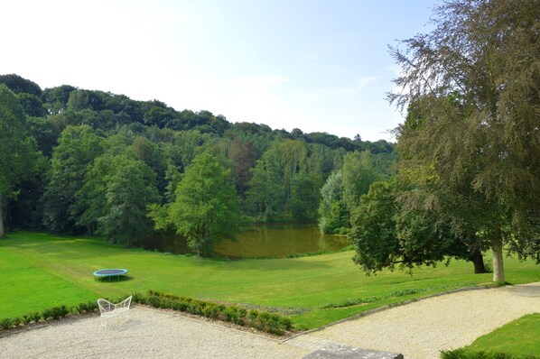 A serene outdoor area with a pond, a trampoline, and a gravel path leading to a seating area. - Marchin Castle With Sauna (Marchin)