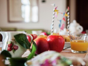 A table with apples, a glass of orange juice, and a teapot.