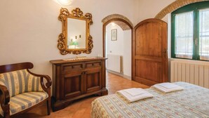Un dormitorio con una cama, un armario de madera, una silla, un espejo y un arco de entrada.