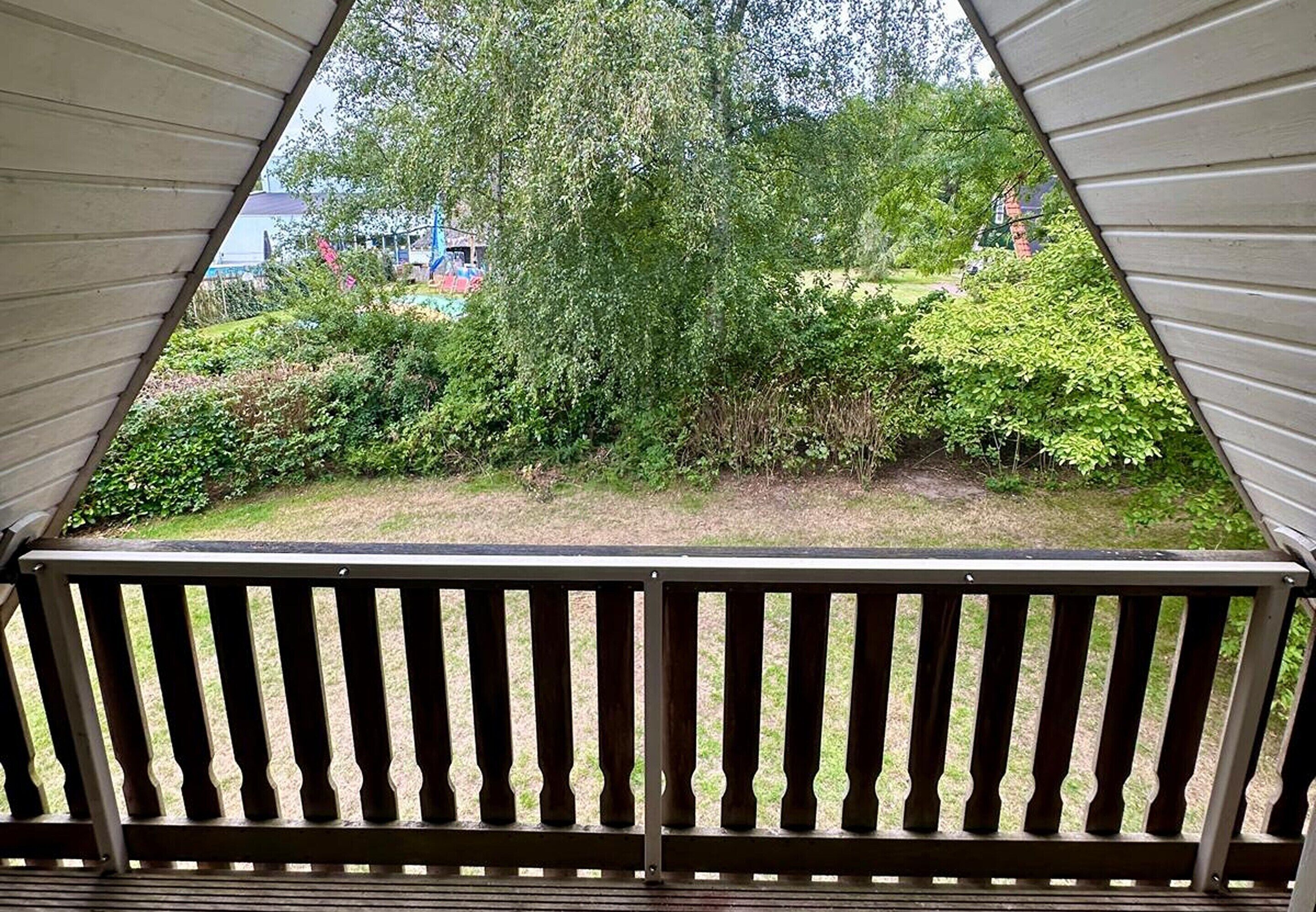 A triangular window with a view of a garden and a building in the background.