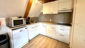 Een keuken met witte kastjes, een magnetron, een koffiezetapparaat en een vaatwasser.