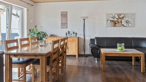 A modern living room with a wooden dining table, black leather sofa, and a floor lamp. - Entspannender Ruckzugsort in Langewiese (Winterberg)