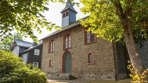 A stone building with a steeply pitched roof and a tower. - Entspannender Ruckzugsort in Langewiese (Winterberg)