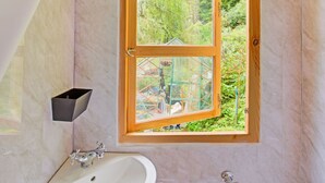 A bathroom with a large window, a sink, and a mirror.