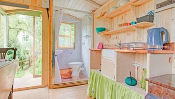 A compact kitchen with wooden shelves, a sink, and a window.