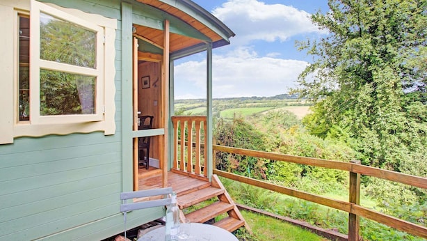 A cozy cabin with a wooden deck and a scenic view of the countryside.