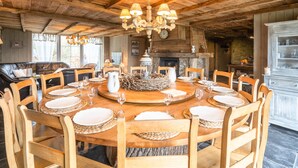 Ein rustikaler Speisesaal mit einem Holztisch, der für eine Mahlzeit gedeckt ist, umgeben von Holzstühlen.