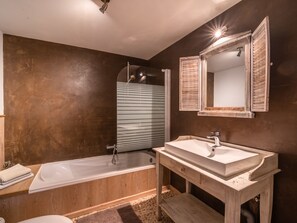 A modern bathroom with a wooden vanity, a bathtub, and a large mirror.