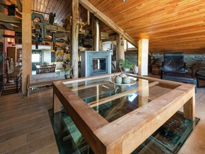 Un intérieur en bois avec une table à plateau de verre, une cheminée et un mur en pierre.